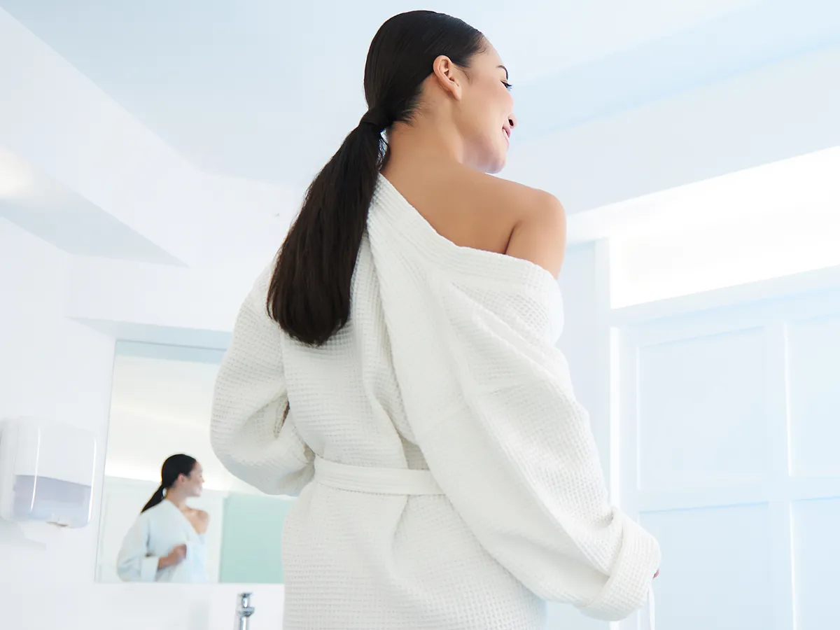 Woman in a white spa robe preparing for a cold plunge wellness session