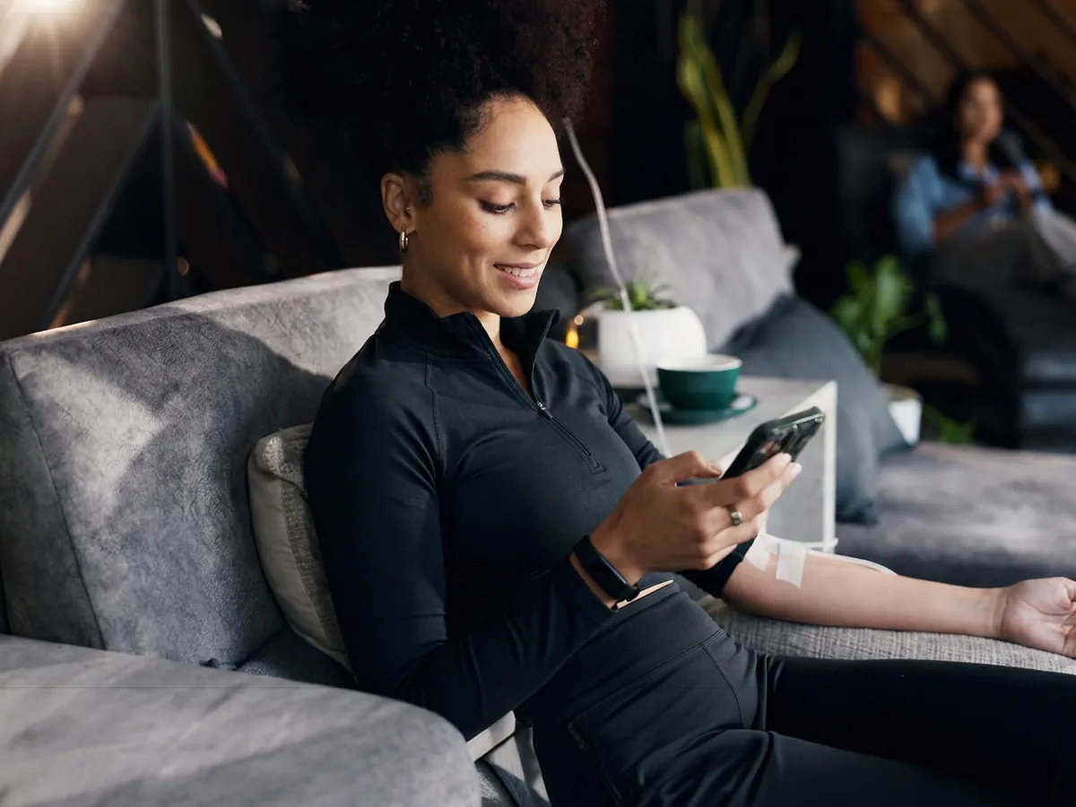 Woman receiving NAD+ IV therapy while relaxing and using her phone